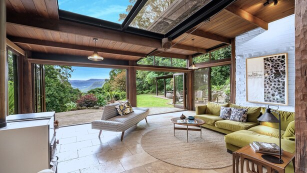 A spacious living area with a large glass wall offering a scenic view of a lush landscape and mountains. - Lyra - Kangaroo Valley (KANGAROO VALLEY)