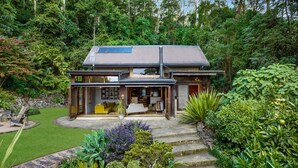 A modern house with a large glass entrance, a solar panel on the roof, and a garden with various plants. - Lyra - Kangaroo Valley (KANGAROO VALLEY)