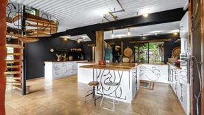 A modern kitchen with a central island, wooden stools, and a loft area above. - Lyra - Kangaroo Valley (KANGAROO VALLEY)