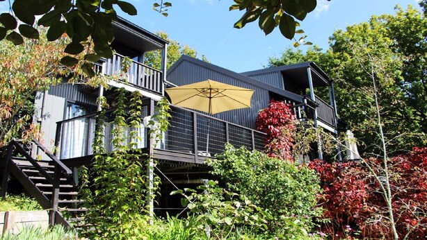 A multi-level building with a balcony and a yellow umbrella. - Cloudsong Chalet 3 - Close to the village centre! (KANGAROO VALLEY)