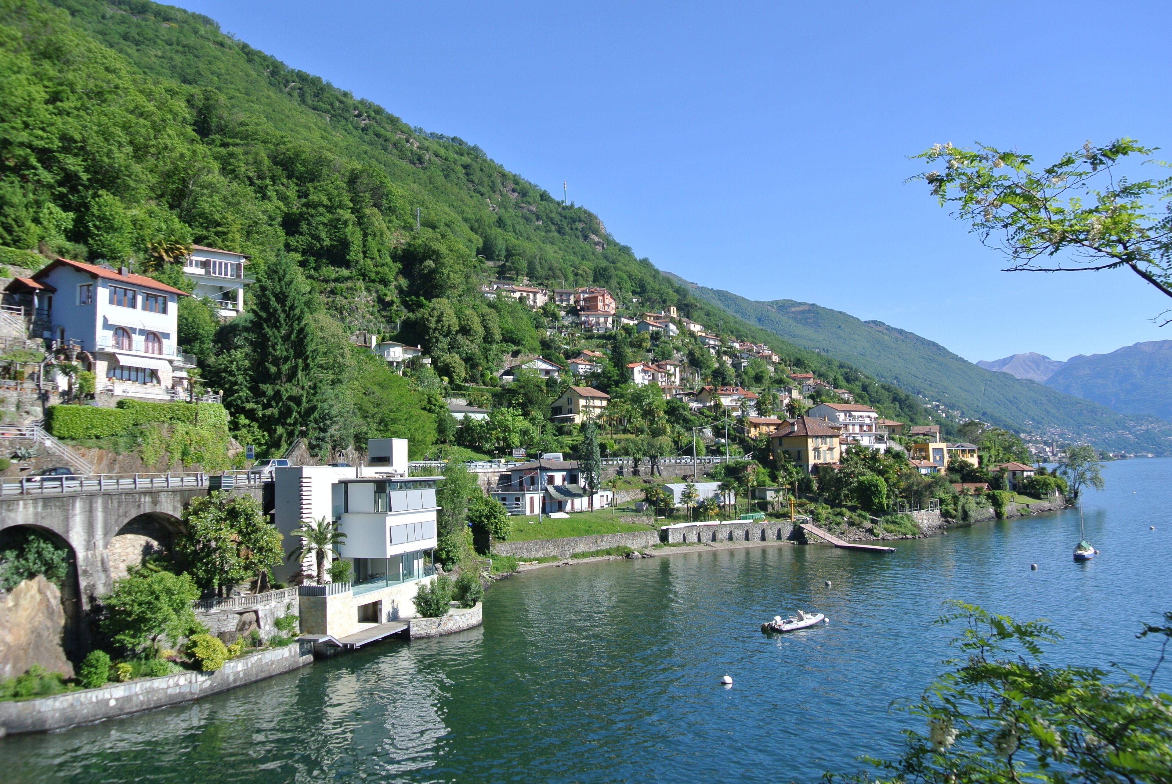 Una cittadina sulle rive del fiume, con case su una collina, un ponte e barche sull'acqua.