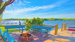 A wooden deck with benches and a fire pit overlooking a lake. - Lakefront • Hot Tub • Walk to Beach & Downtown (Lake Odessa)