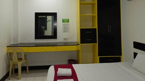 Une chambre d’hôtel comprenant un lit, un bureau, une chaise, une armoire et un miroir.