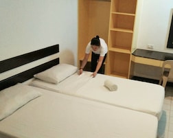 A hotel room with two beds, a desk, and a wardrobe.