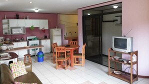 A compact living space with a kitchenette, a dining area, a sofa, and a television.