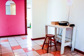A room with a white desk, a wooden stool, a telephone, and a Philips stereo system.