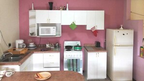 A compact kitchen with white cabinets, a stove, a microwave, and a refrigerator.