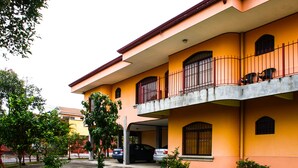 A two-story building with a balcony, a covered parking area, and a well-maintained lawn.