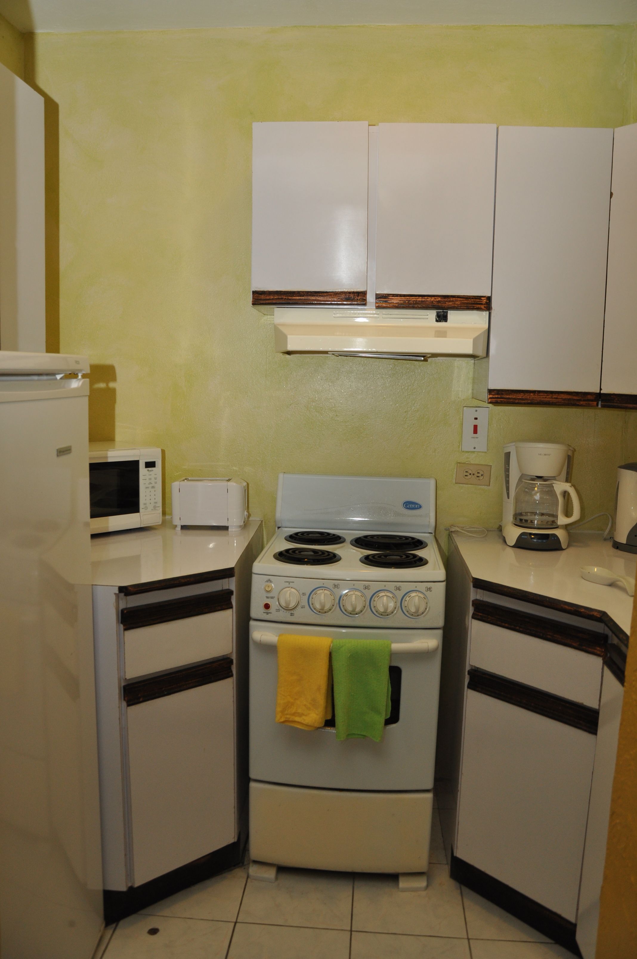 A compact kitchen with a microwave, toaster, stove, and coffee maker.