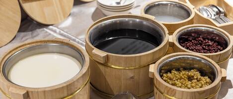 Various wooden containers with different contents, including a bowl of milk, a bowl of beans, and a bowl of black liquid.