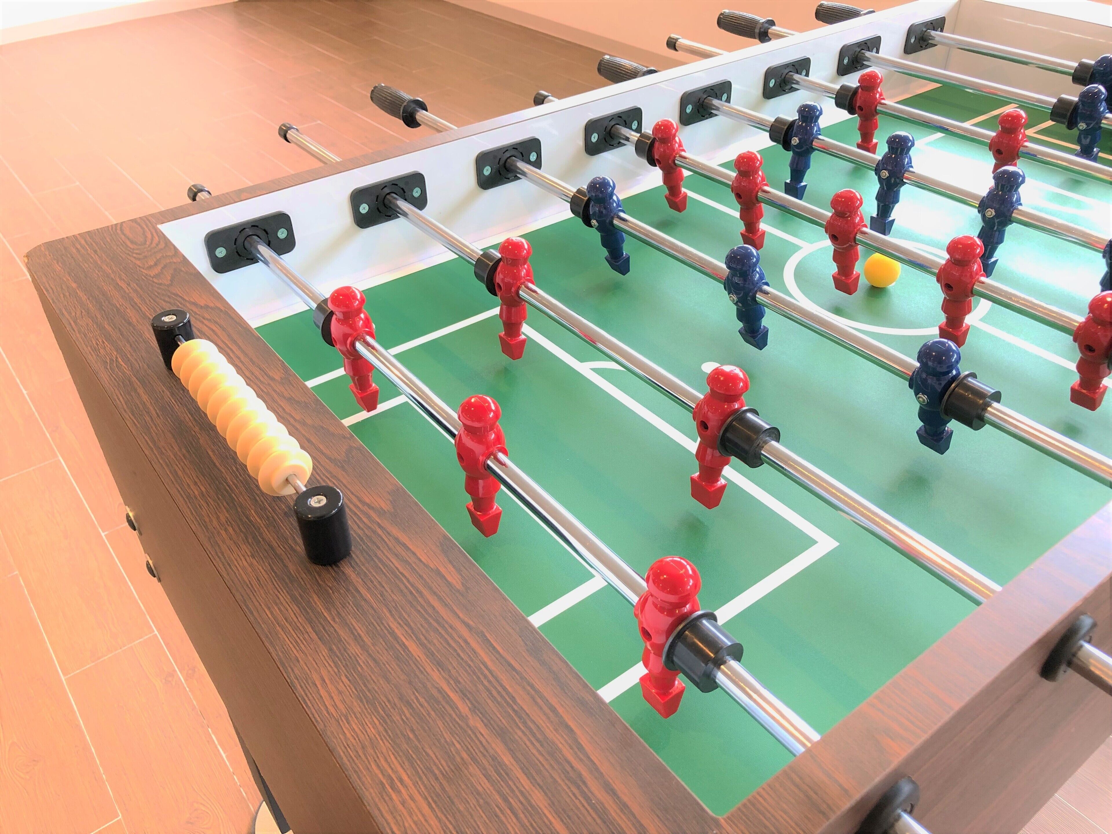 A foosball table with a wooden frame and a green playing surface.