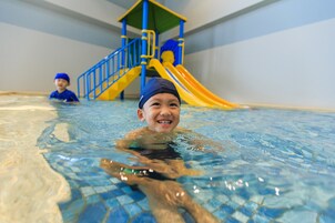 Una piscina interior con una estructura de juegos al fondo.