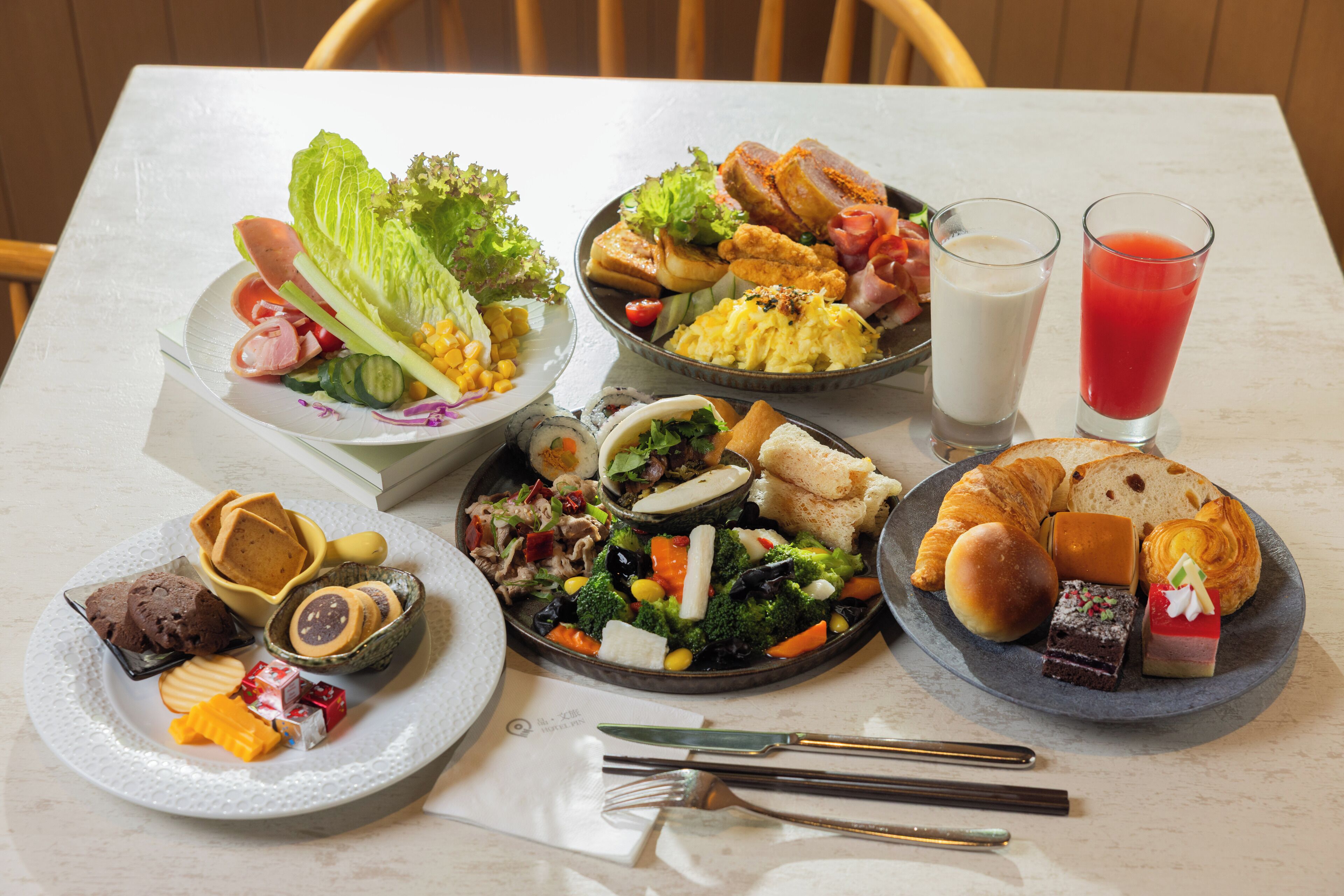 A table with various food items including salads, pastries, and desserts.