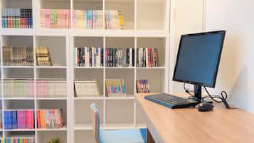 Un espacio de estudio con escritorio, computadora y estanterías llenas de libros.