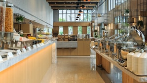 A buffet area with multiple food stations, a central serving counter, and a modern interior design with wooden elements and large windows. - Hotel PIN Jiaoxi (Jiaoxi)