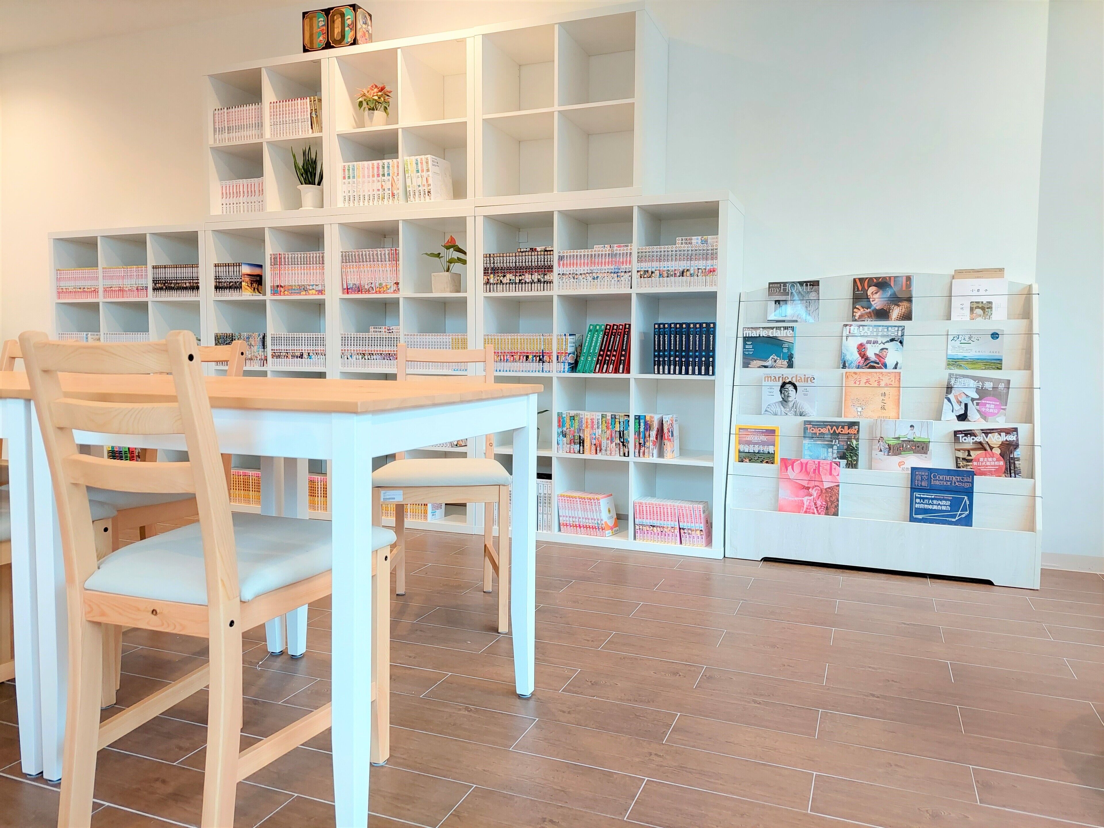 A library with bookshelves, a wooden table, and chairs.
