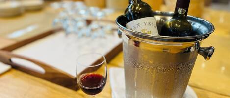 Una mesa con una botella de vino, una copa de vino y una bandeja con copas.