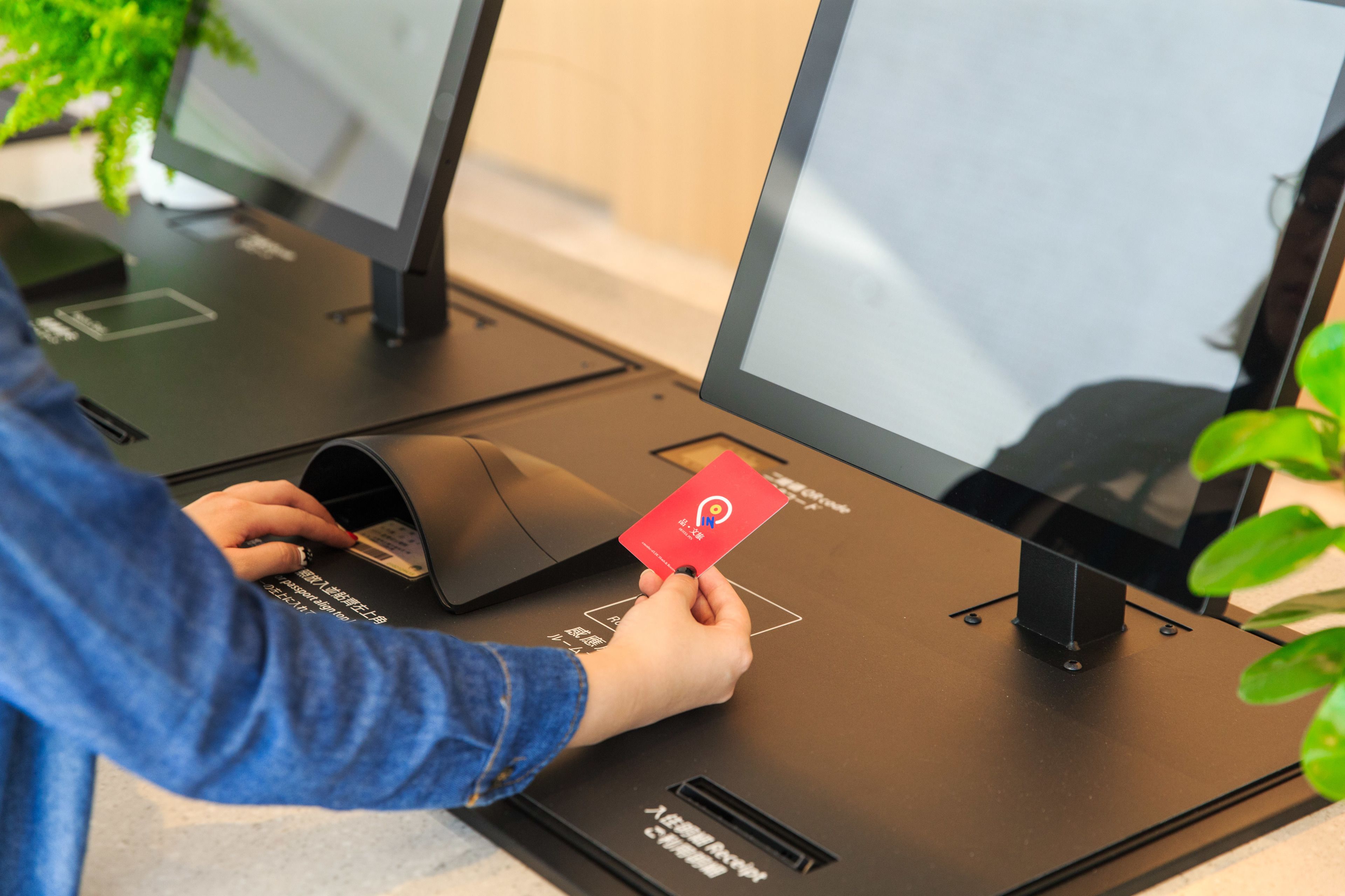 A person using a self-service kiosk with a red card, likely for payment or information retrieval.