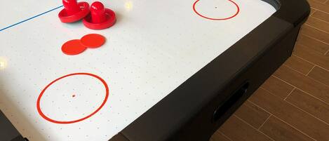 Un juego de hockey de mesa con fichas rojas sobre una mesa blanca con círculos rojos.