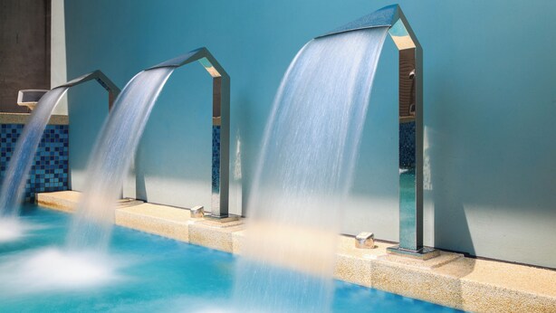 A pool with three water features, each with a different design, against a blue wall. - Hotel PIN Jiaoxi (Jiaoxi)