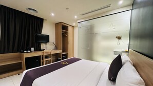 A hotel room with a bed, a desk, a chair, a television, and a wardrobe.