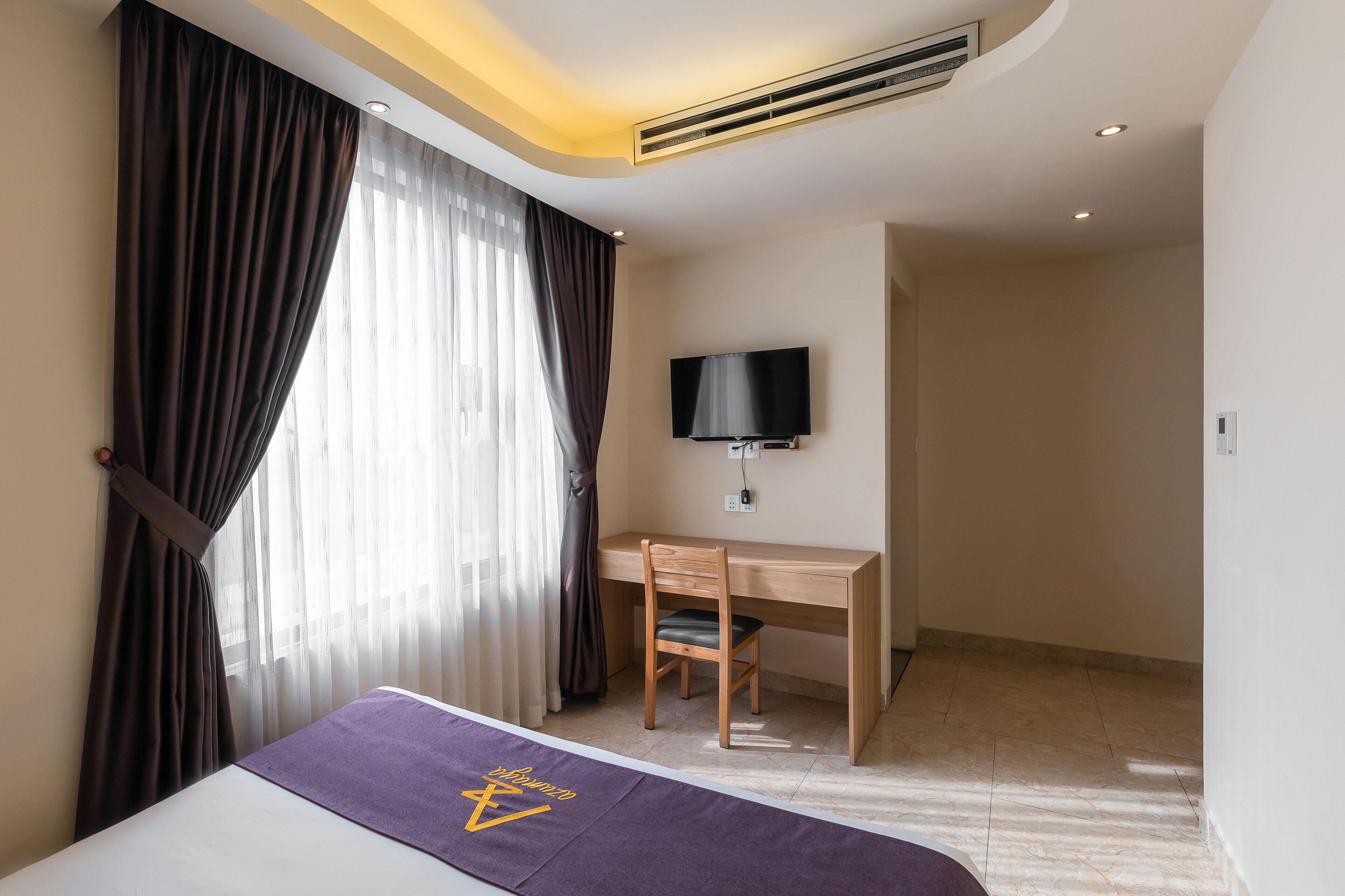 A hotel room with a bed, a desk, and a TV.