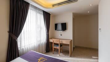 A hotel room with a bed, a desk, and a TV.