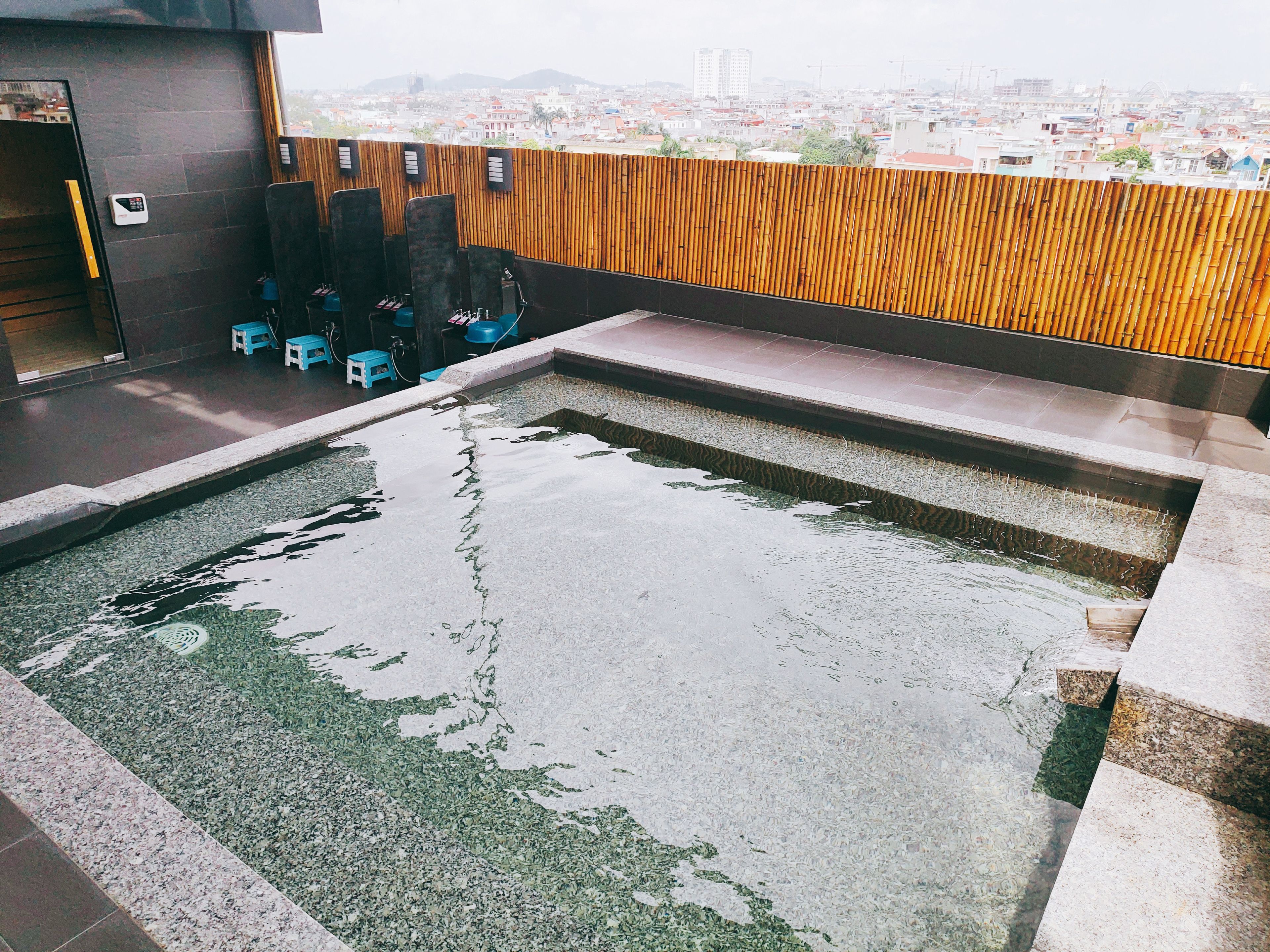 A rooftop pool with a wooden wall and a city view.