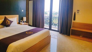 A hotel room with a large bed, a nightstand, a lamp, and a view of the outside balcony.