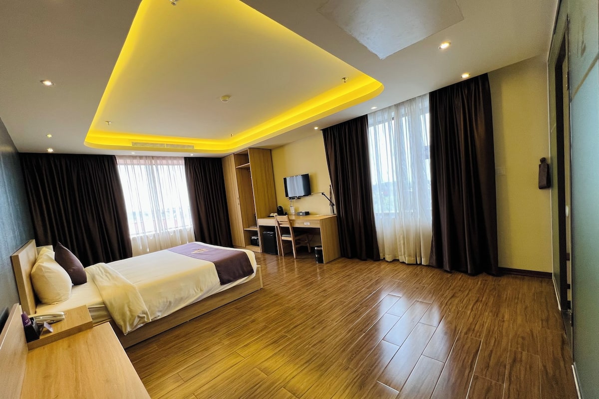 Ein Hotelzimmer mit Bett, Schreibtisch und Fernseher.