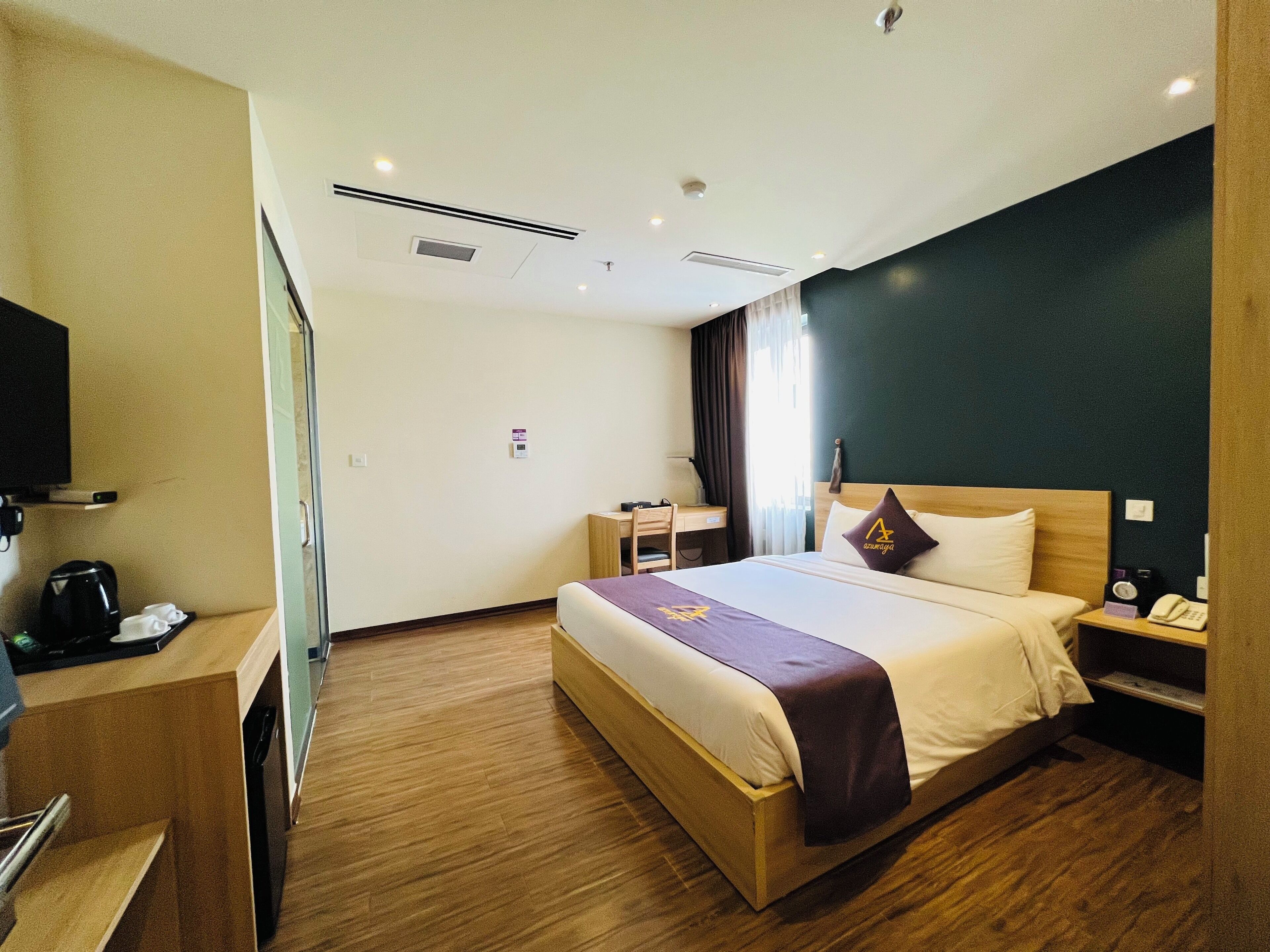 A hotel room with a bed, bedside table, desk, and a television.