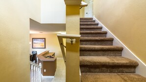 A carpeted staircase with a handrail, leading to a landing with a desk and chair. - Bella Vida Home 2 U- Gru (Kissimmee)