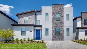 A modern two-story residential building with a blue door, stone facade accents, and a well-maintained lawn. - Storey Lake Exec Villas- 2965fs (Kissimmee)