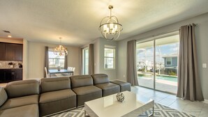 A modern living room with a sectional sofa, a white coffee table, and a chandelier. - Champions Gate Home 2 U- Thor - Cg1561 (Davenport)