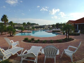 A swimming pool with lounge chairs and palm trees.