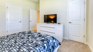 Ein Schlafzimmer mit einem Bett, einem Schminktisch, einem Fernseher und zwei Türen.