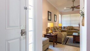 A living room with a sofa, two lamps, a ceiling fan, and a door.