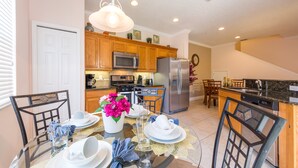 A modern kitchen with wooden cabinets, stainless steel appliances, and a dining area set for a meal.