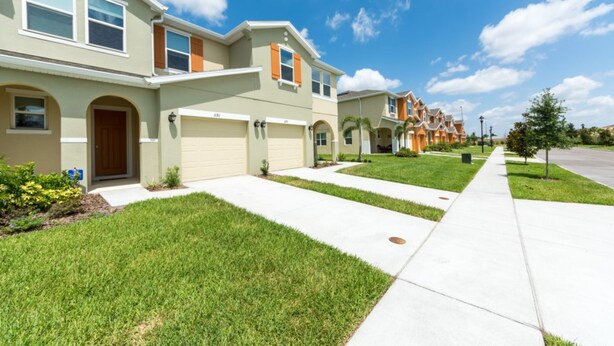 A row of modern townhouses with a well-maintained lawn and a clear sky.