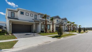 A modern two-story residential building with a garage, palm trees, and a well-maintained lawn. - Sonoma Resort Home 2 U- Storm (Kissimmee)