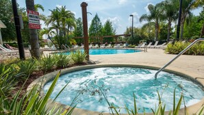 Un bain à remous entouré de chaises longues et de palmiers.
