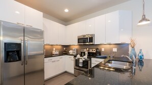 A modern kitchen with stainless steel appliances, white cabinetry, and a black granite countertop. - Serenity Home 2 U- Winter (Clermont)
