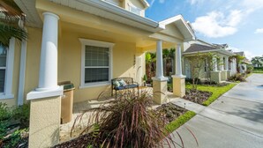 A residential building with a covered porch, a bench, and a small garden area. - Serenity Home 2 U- Winter (Clermont)