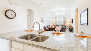 Een moderne keuken met granieten aanrecht, een dubbele spoelbak en een eethoek met een tafel voor vier personen.