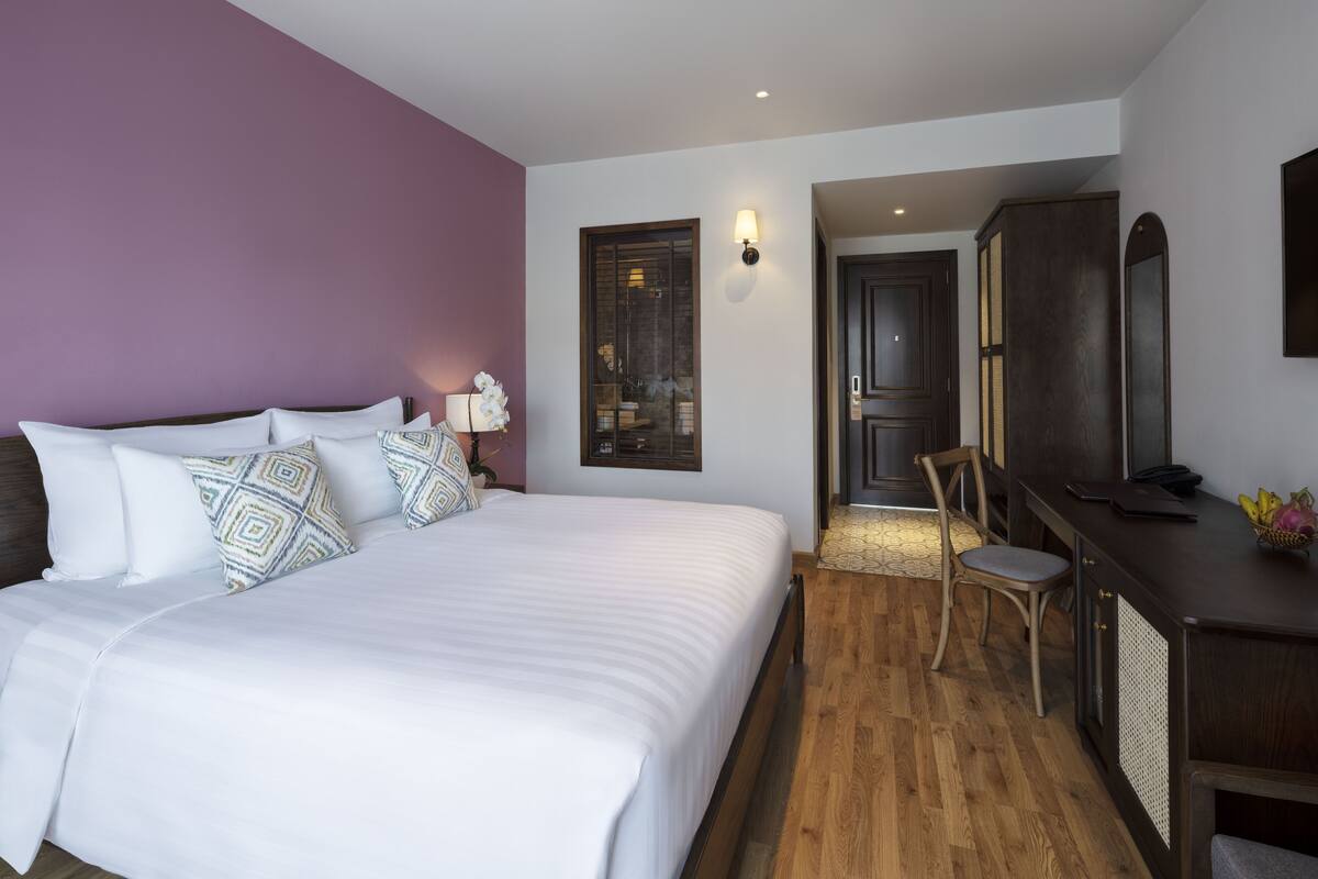 Een slaapkamer met een groot bed, een bureau en een kledingkast.