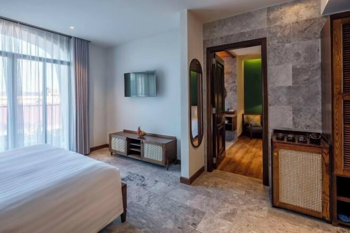 Hotelkamer met een bed, een televisie, een spiegel, een console en een deur naar de badkamer.
