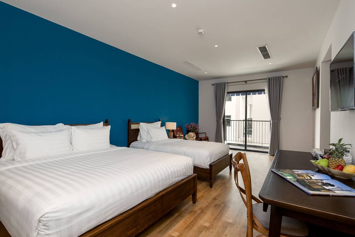 Een hotelkamer met twee bedden, een eettafel en uitzicht op de omgeving.