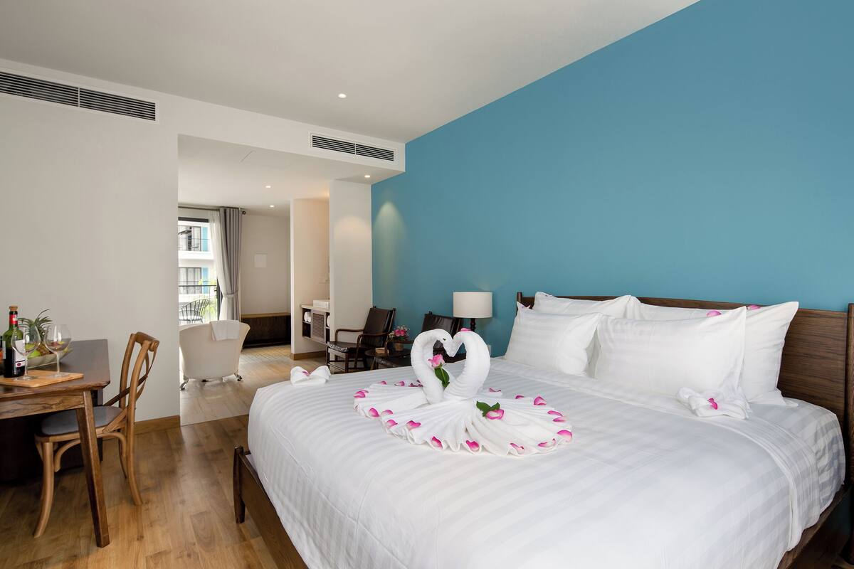 Hotelkamer met een groot bed, een bureau met stoel, een badkamer en uitzicht op buiten.