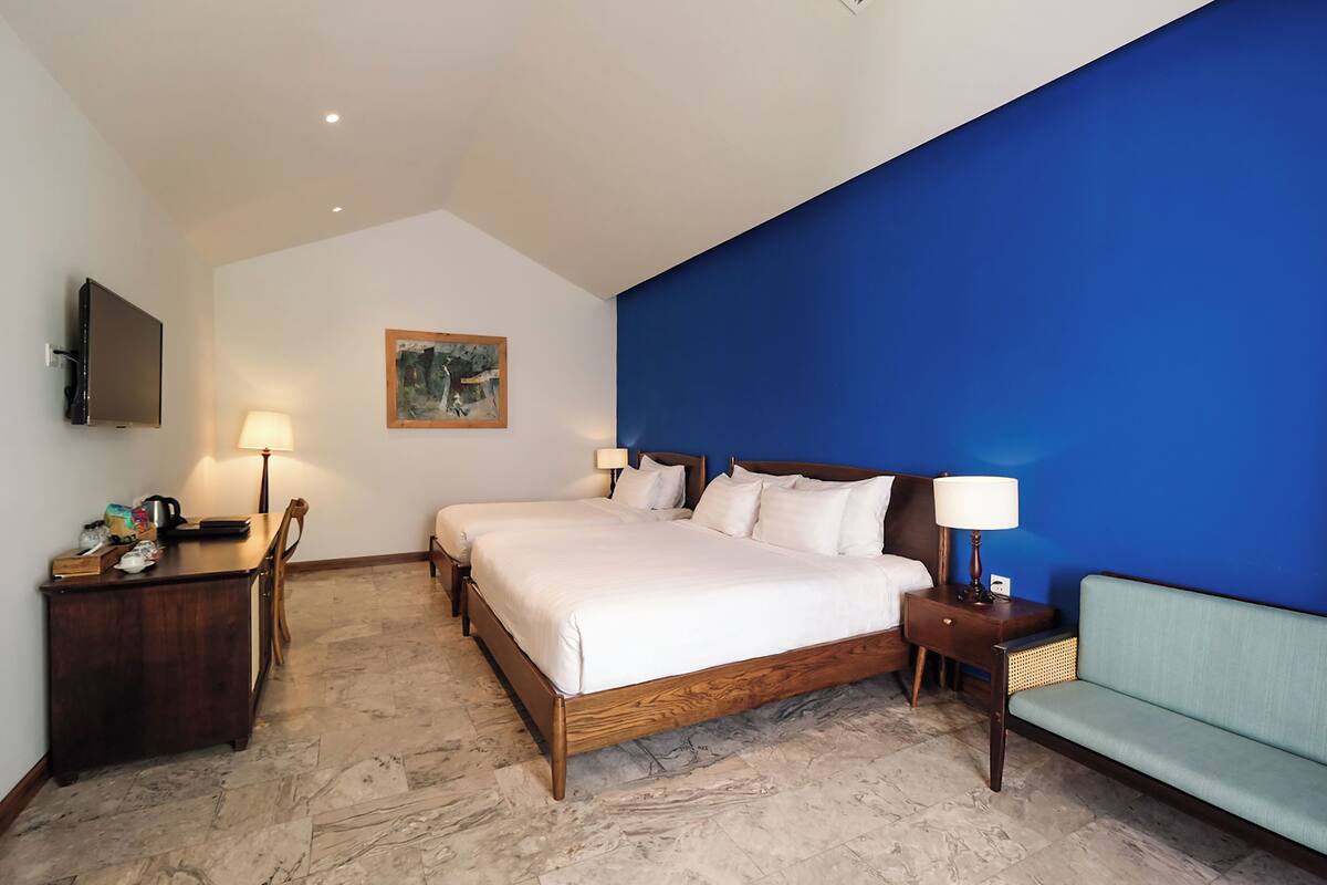 Hotelkamer met een groot bed, bureau, stoel, bank, televisie en een schilderij aan de muur.