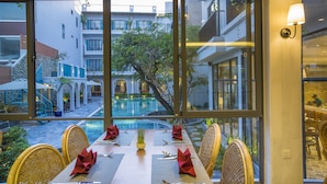 A dining area with a view of a swimming pool and buildings.
